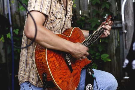 person holding brown guitar outdoor photo