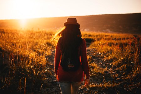 woman walking on grass plains during sunset photo