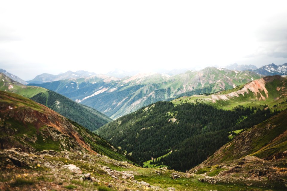 grass field near mountain range under cumulus clouds photo