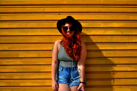 A redhead woman standing in front of a yellow wall.