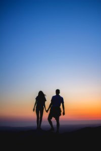 man and woman holding hands in silhouette photography photo