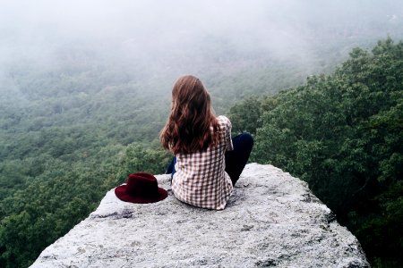 woman sitting on top of gray rock photo
