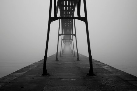 grayscale photograph of bridge between body of water photo