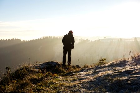 man standing on cliff near trees during daytime photo