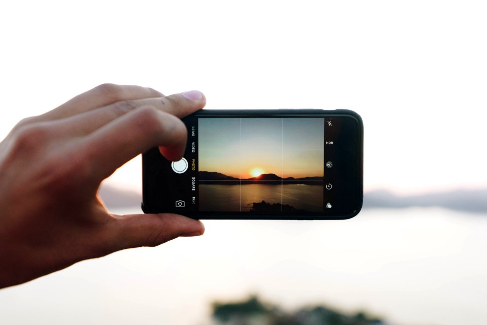 person taking picture on mountain with sun