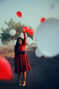 focus photography of woman standing on road raising her left hand photo