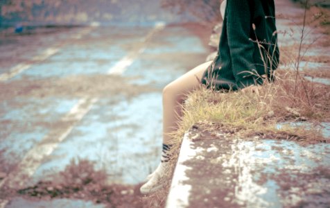 woman sitting on concrete barrier