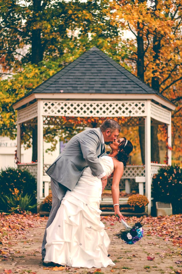 groom kissing bride near white gazebo