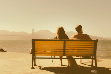 man and woman sitting on bench beside body of water photo