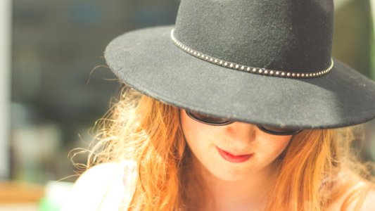 woman looking down wearing black bowler hat photo