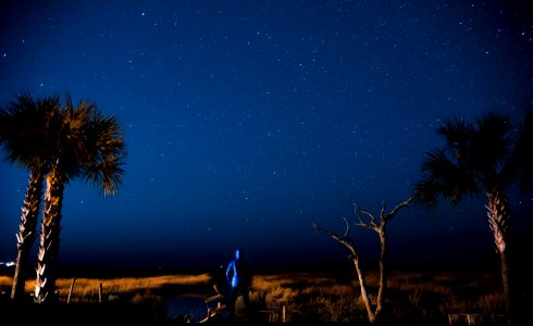 photo of person standing and looking clouds with stars