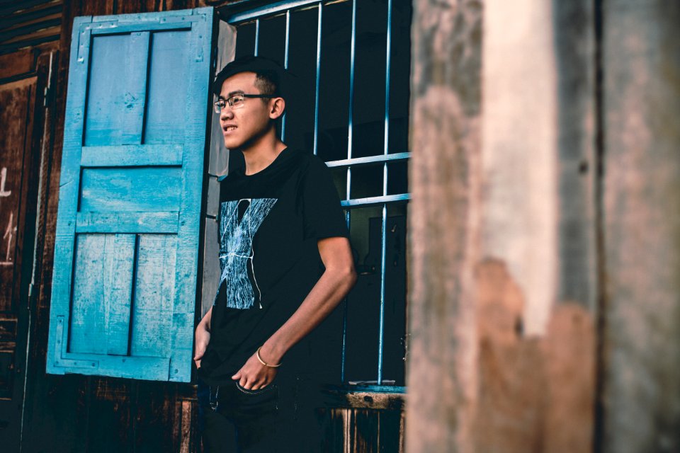 man wearing black crew-neck shirt near blue wooden window photo