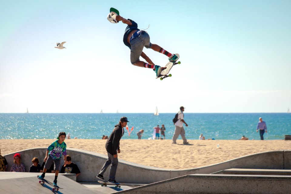 three people playing skateboard beside seashore during daytime