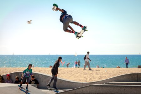 three people playing skateboard beside seashore during daytime photo