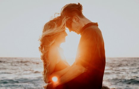 man and woman hugging near sea during golden hour photo