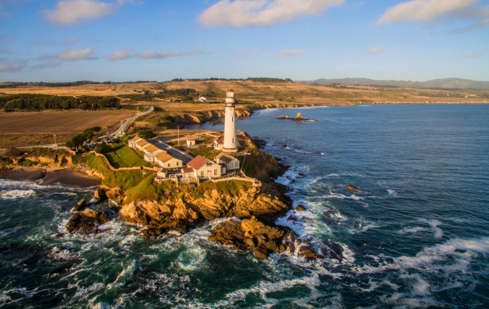aerial photo of a white lighthouse and body of wate