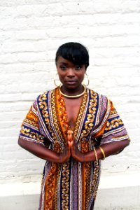 An African American woman wearing hoop earrings, putting her hands together in a prayer.