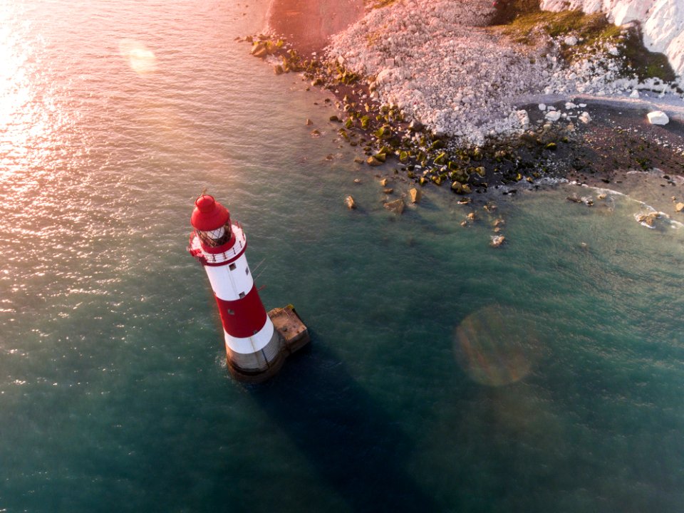 white and red lighthouse in body of water near shore