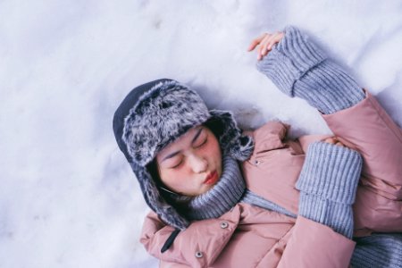 woman lying on white snow during daytime photo