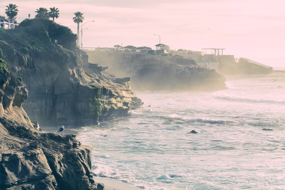 waves splashing on shore near cliff photo