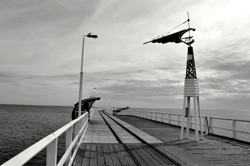 wooden wind vane on bridge near the body of water