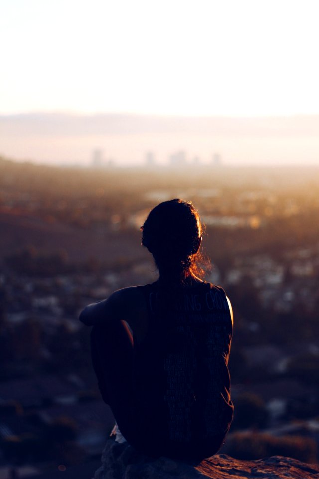 woman sitting on brown rock during daytime