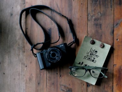 flat lay photography of black MILC camera and eyeglasses on brown table photo