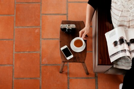 person sitting on sofa while reading brochure holding teacup photo