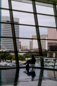 silhouette of person sitting besides clear glass wall inside building photo