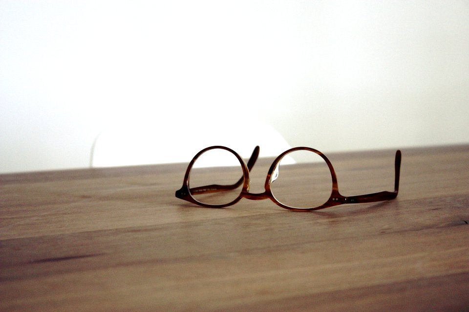 eyeglasses with brown frames on brown wooden surface