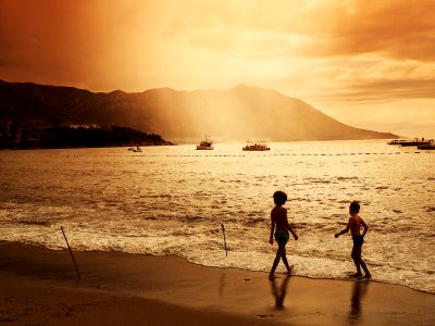 two children walking on beach during sunset