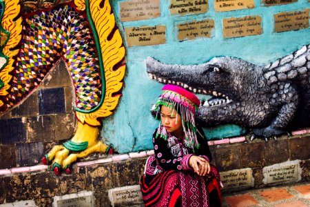 girl wearing multicolored traditional dress sitting near the wall photo
