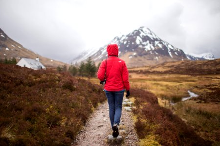 woman walking on brown pathway near house