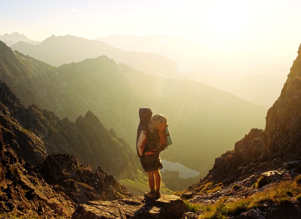 climber standing on rock near overlooking view of mountain at daytime