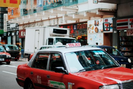 red and white taxi sedan running on road near 7 Eleven store signage photo