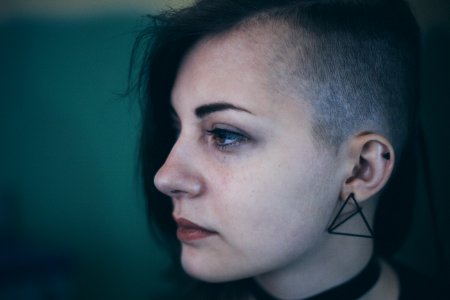 Woman with an edgy shaved haircut looks sad and defeated photo