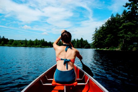 woman riding on boat while paddling under blue sky during daytime photo