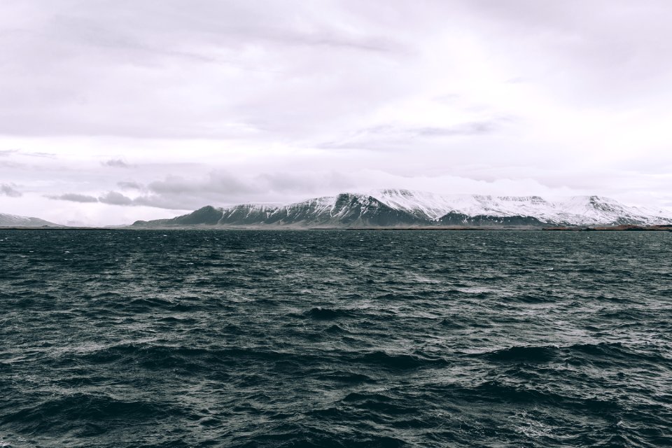 body of water near mountain covered with snow