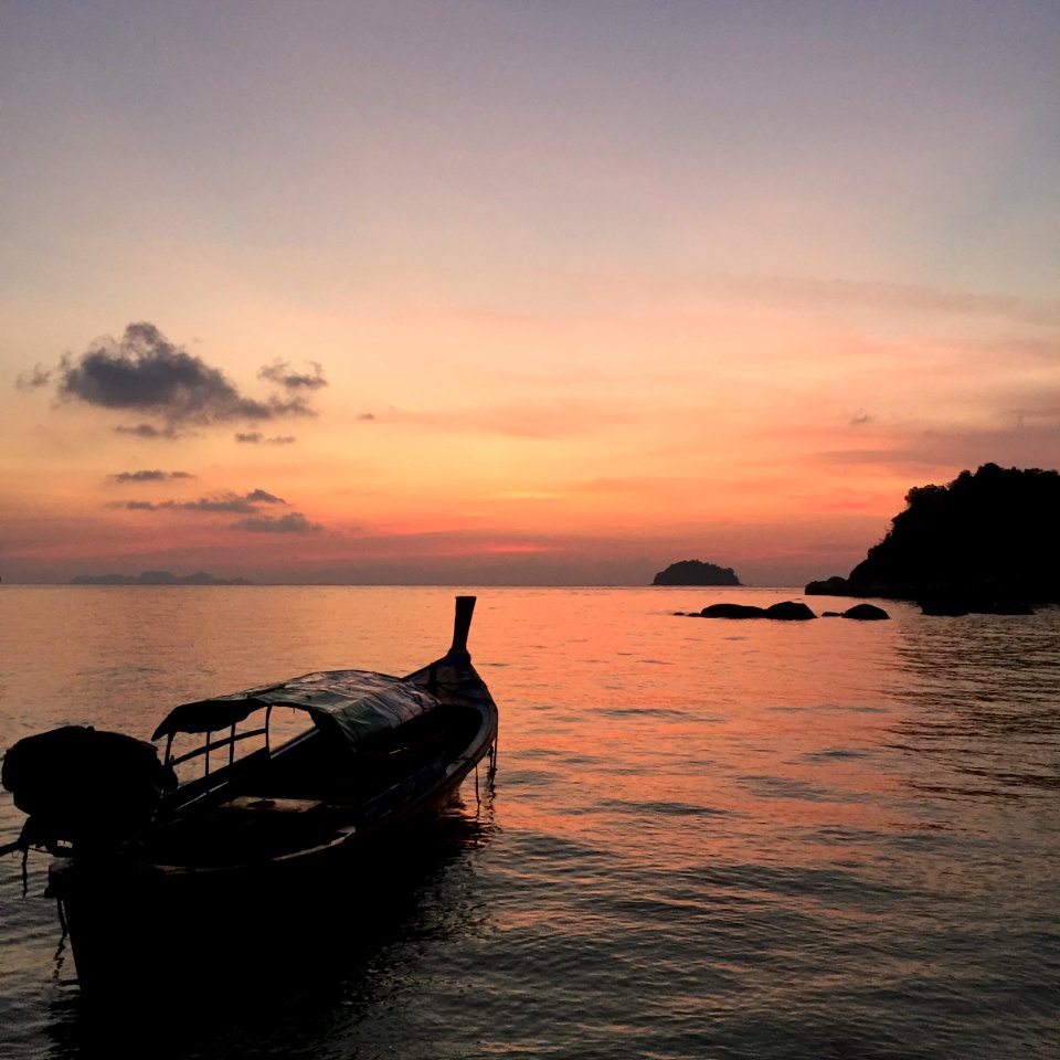 silhouette of boat on sea during sunset