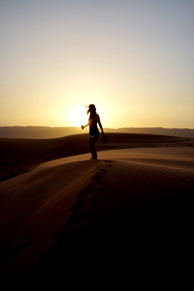 woman standing on sand during sunset