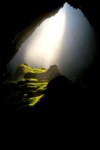 person on top of rock formation inside cave photo