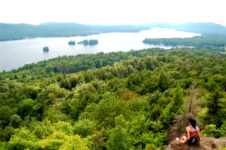 photo of woman carrying bag sitting on cliff