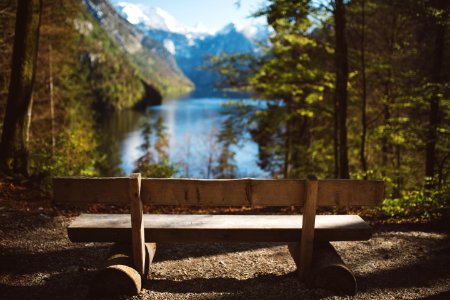 empty brown wooden bench facing body of water and mountain photo
