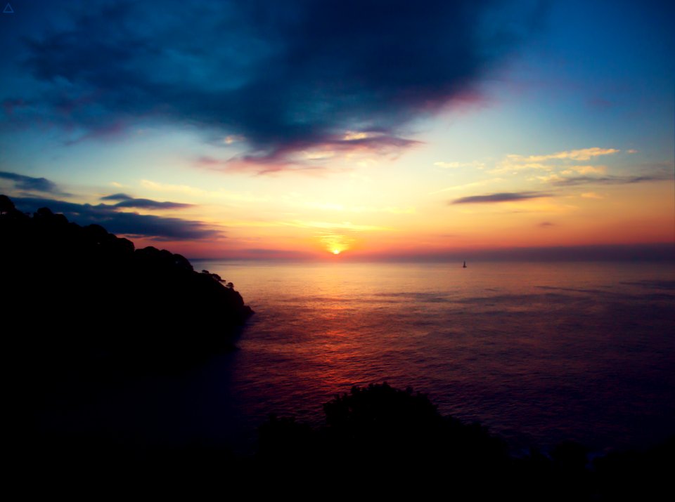 ocean and mountain under cloudy sky during golden hour
