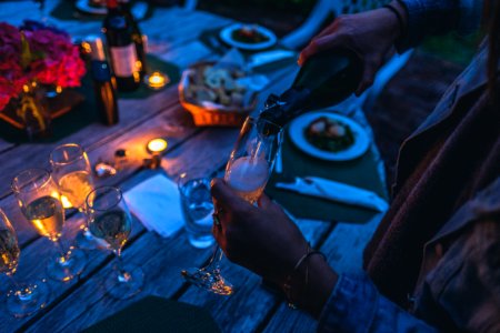 person putting wine on flute glass