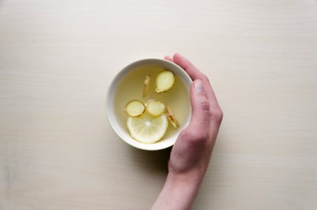 person holding white bowl with sliced lime and ginger inside photo