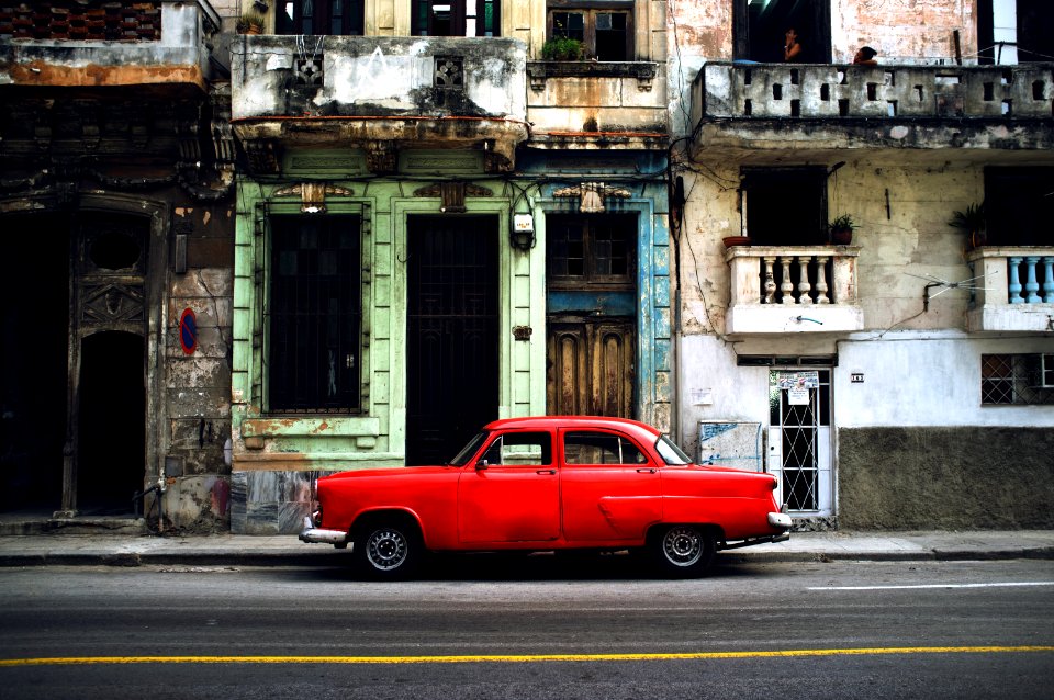 red car parked on road in front concrete building
