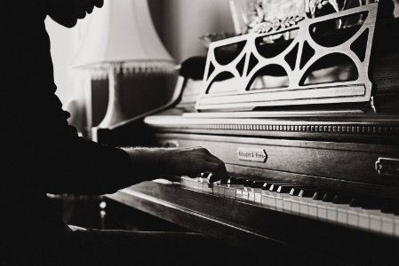 greyscale photo of man playing spinet piano close-up photo photo