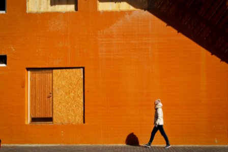 man walking beside orange building at daytime photo