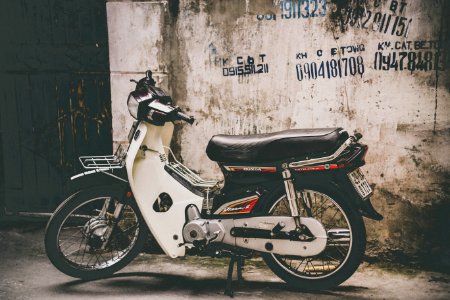 white and black underbone motorcycle parked near the wall photo